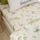 This Sleepy Dino Toddler Fitted Sheet by Catherine Lansfield features a variety of friendly dinosaurs roaming through a prehistoric landscape.